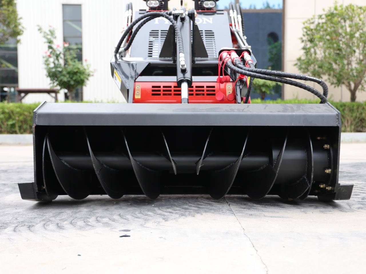 A TYPHON skid steer trench filler attachment is designed to fill in trenches or ditches created previously. The attachment is typically a bucket with a flat bottom and a curved back that can be adjusted to the width of the trench.